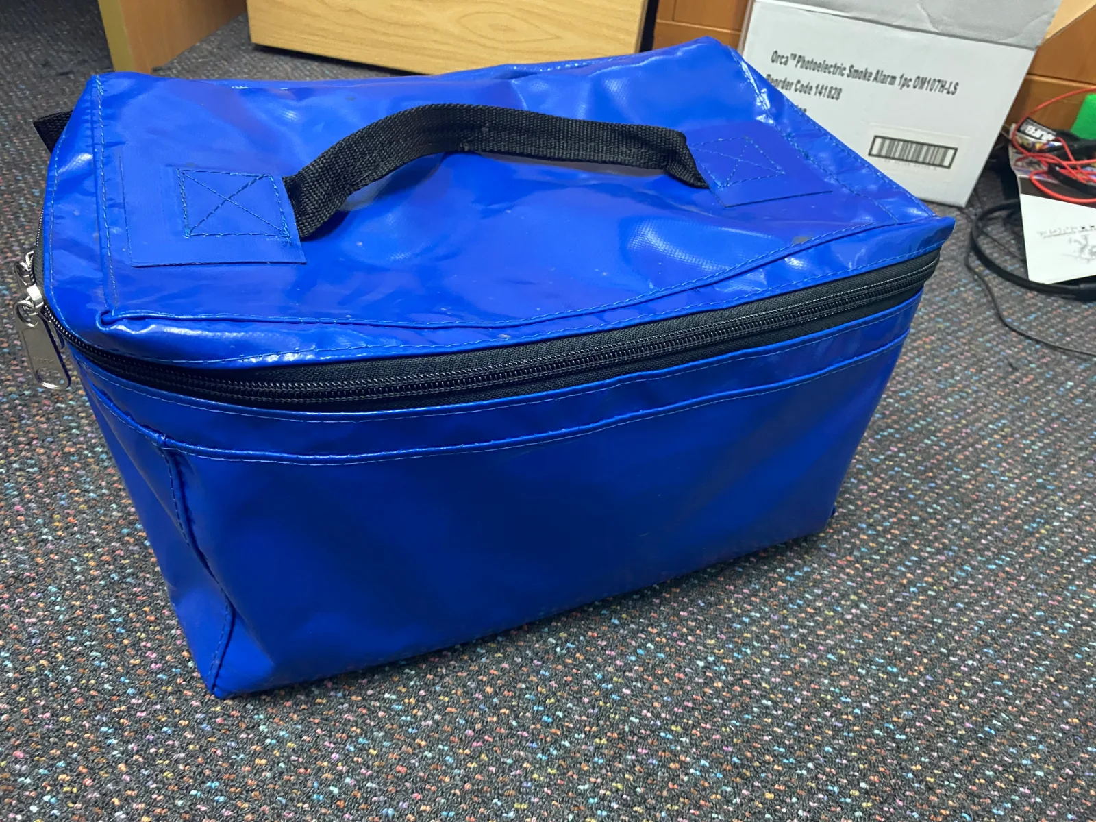 A blue PVC box bag with a zip round the top and a webbing carry handle