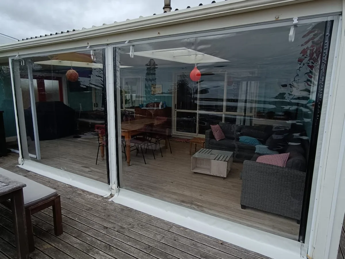 Clear PVC blinds down in their side tracks, closing in a covered deck
